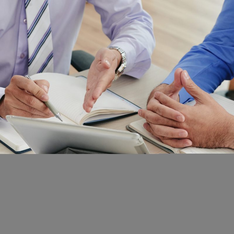 Close-up image of coworkers discussing data on tablet computer screen