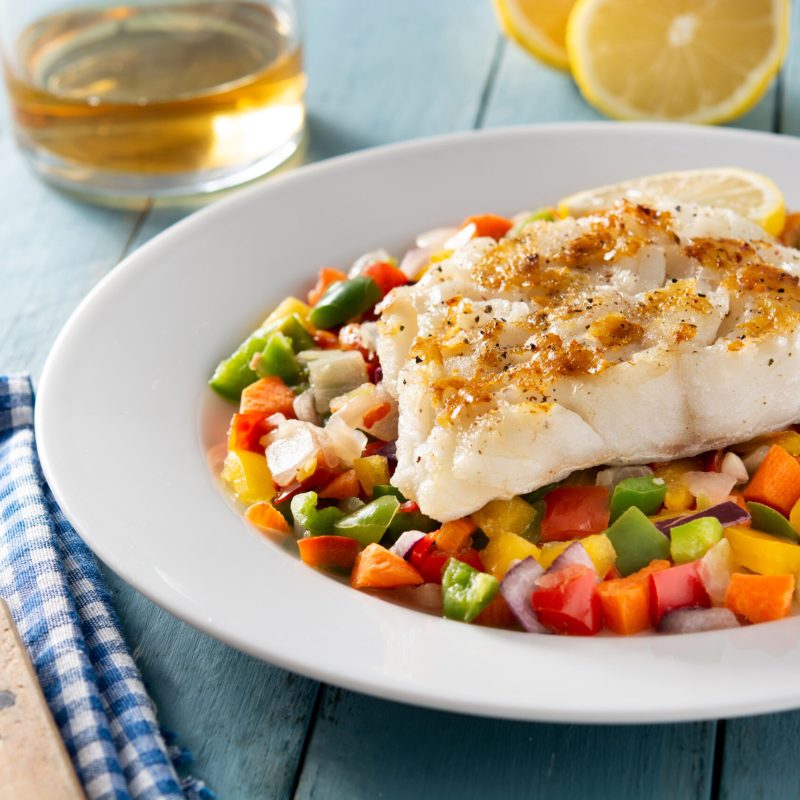 Grilled cod with vegetables on blue wooden table